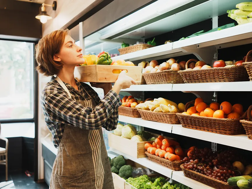 Grocery store employee restocking produce